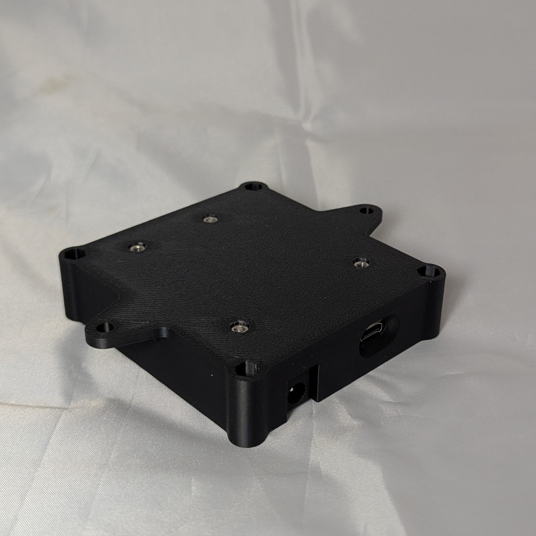 The bottom of a black electronic enclosure on a white background