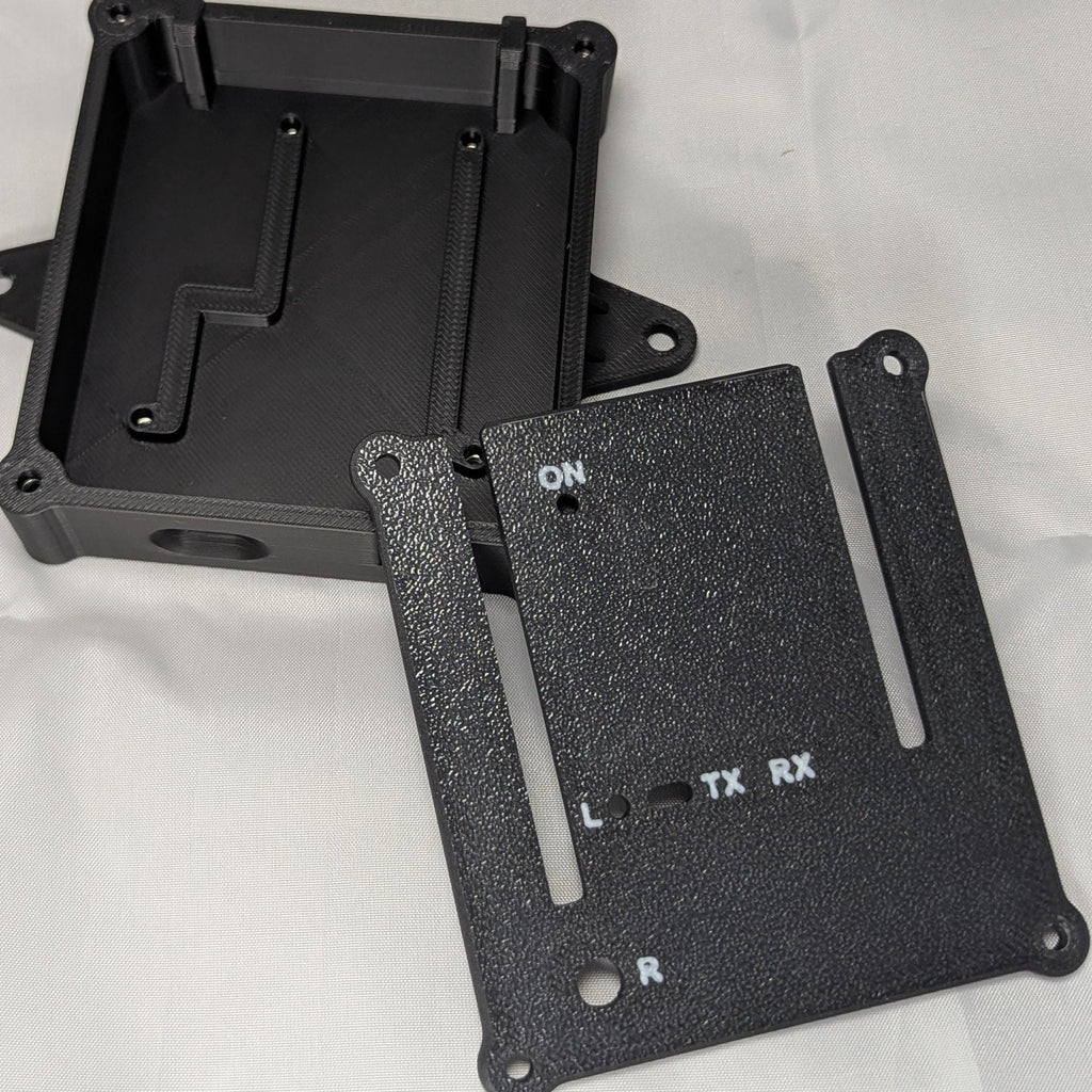 Black electronics enclosure with white text for status LED ports with the lid removed and off to one side on a white background