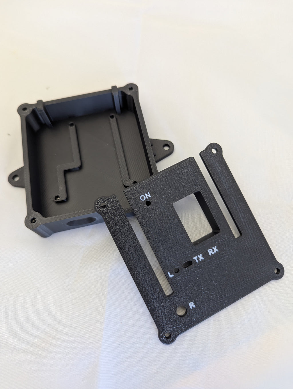 Black electronics enclosure with the lid removed and off to one side on a white background