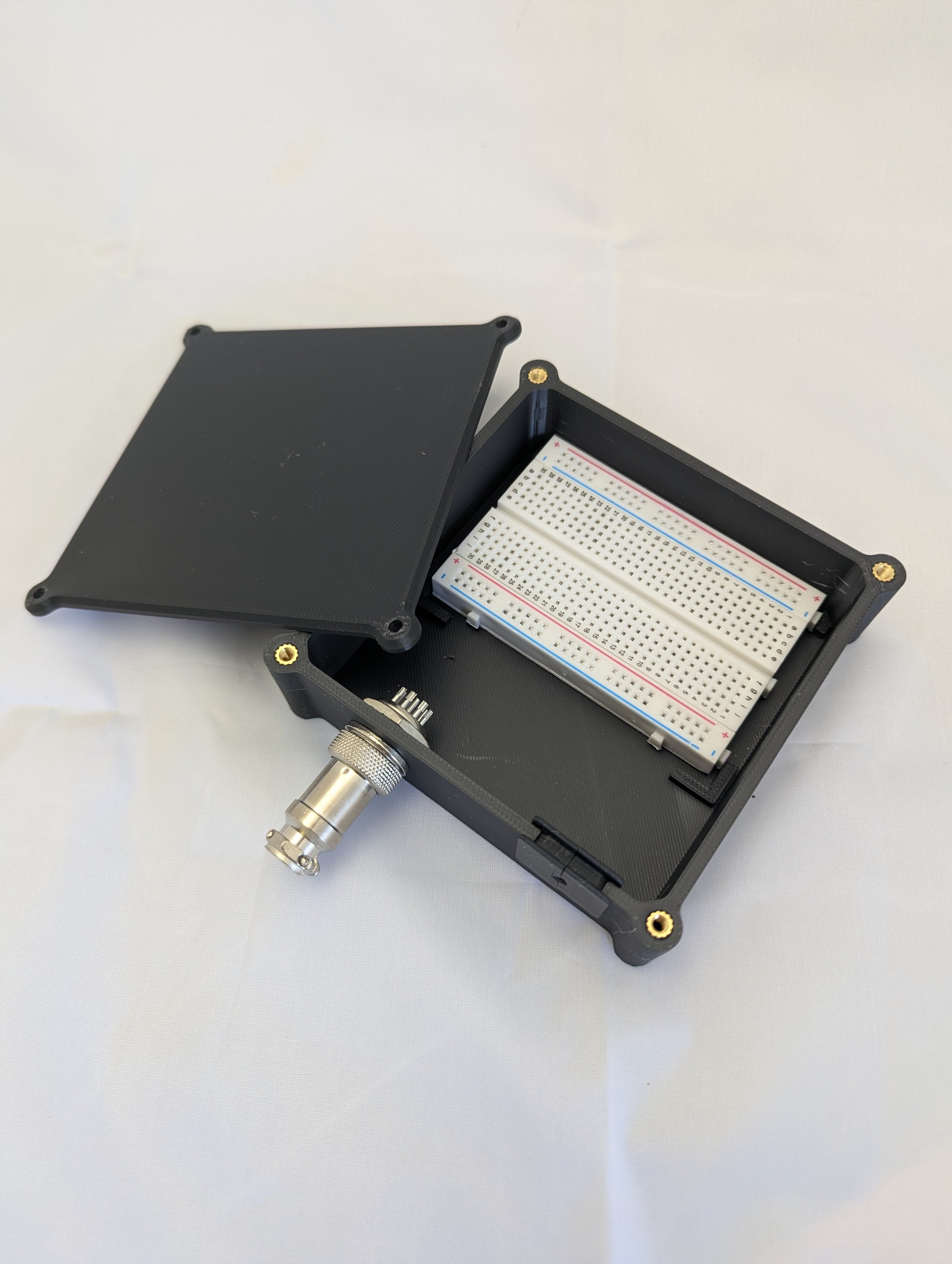 A breadboard housed in a black electronics enclosure with a side mounted connector and USB cable strain relief.