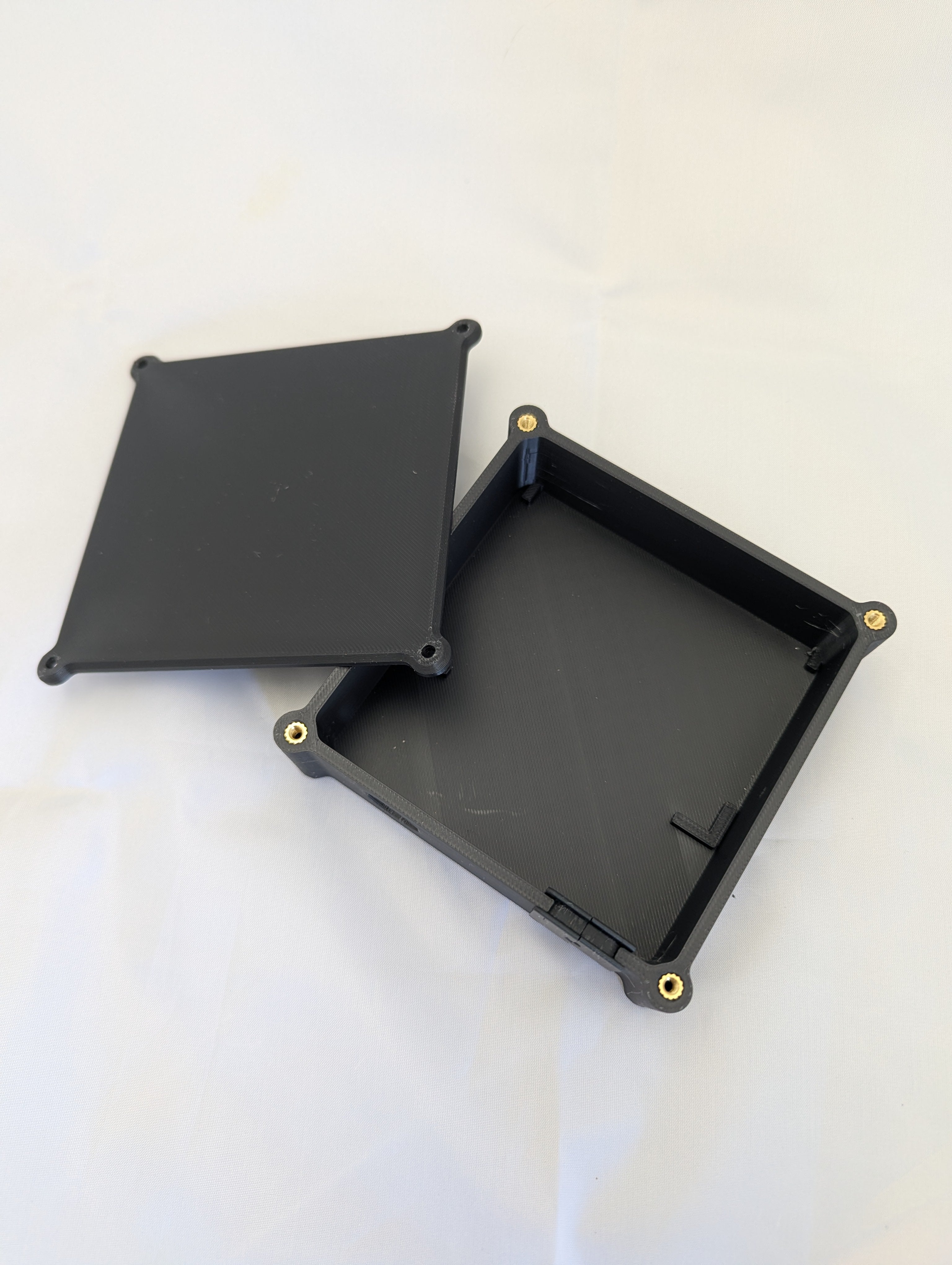 A black electronics enclosure with the lid removed and off to one side.